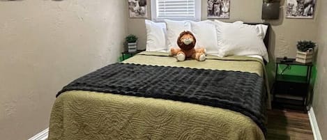 Un dormitorio con cama, aire acondicionado de pared, ventana con persianas y pared decorada con motivos de animales.