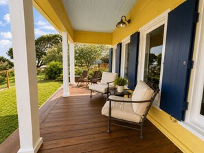 Eine überdachte Veranda mit Holzboden, weißen Säulen und blauen Fensterläden.
