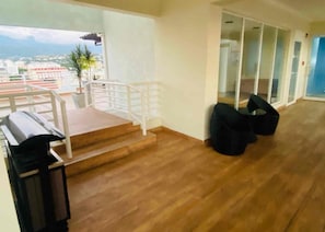 Una habitación con un piano, una escalera y vista a la ciudad.
