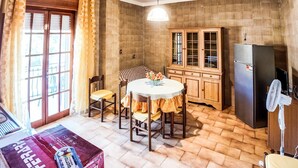 Una cocina con mesa y sillas, armarios de madera, un refrigerador y un ventilador.