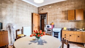 Una cocina compacta con armarios de madera, una mesa de comedor con mantel estampado, un microondas y un horno pequeño.