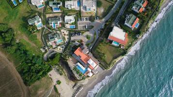 Vista aérea de una zona residencial costera con varias casas, una playa y una carretera.