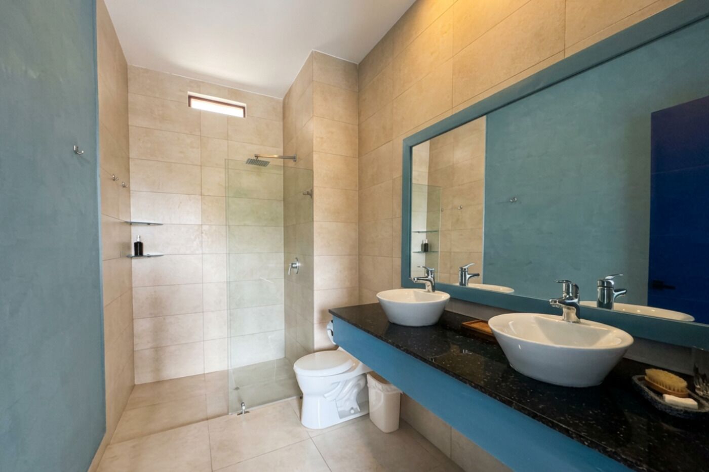 A modern bathroom with a glass shower enclosure, two sinks, and a large mirror.