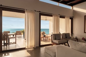A modern living room with a large sliding glass door leading to a balcony with a view of the ocean.