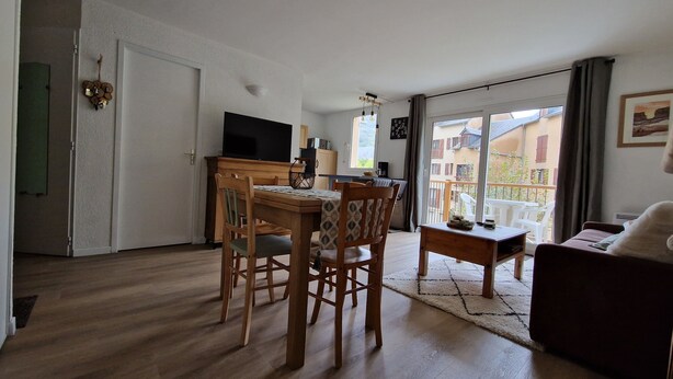 A modern living room with a dining area, a flat-screen TV, and a balcony with a view. - APARTMENT NEAR LUZ SAINT SAUVEUR 4/5 -PERSON APARTMENT (Esquièze-Sère)