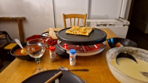 A dining table with a portable stove, a pan, a bowl, and a plate with a piece of food. - APARTMENT NEAR LUZ SAINT SAUVEUR 4/5 -PERSON APARTMENT (Esquièze-Sère)