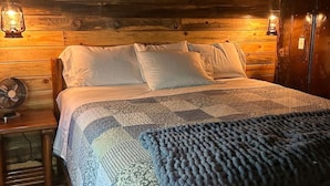 A wooden cabin-style bedroom with a bed, two bedside lamps, and a fan. - Western cabin in Blanchard, OK (Blanchard)
