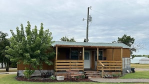 A small wooden cabin with a porch, a door, and a window. - Western cabin in Blanchard, OK (Blanchard)