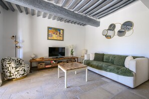 Un salon avec un canapé, une table basse, un téléviseur et un tableau accroché au mur.