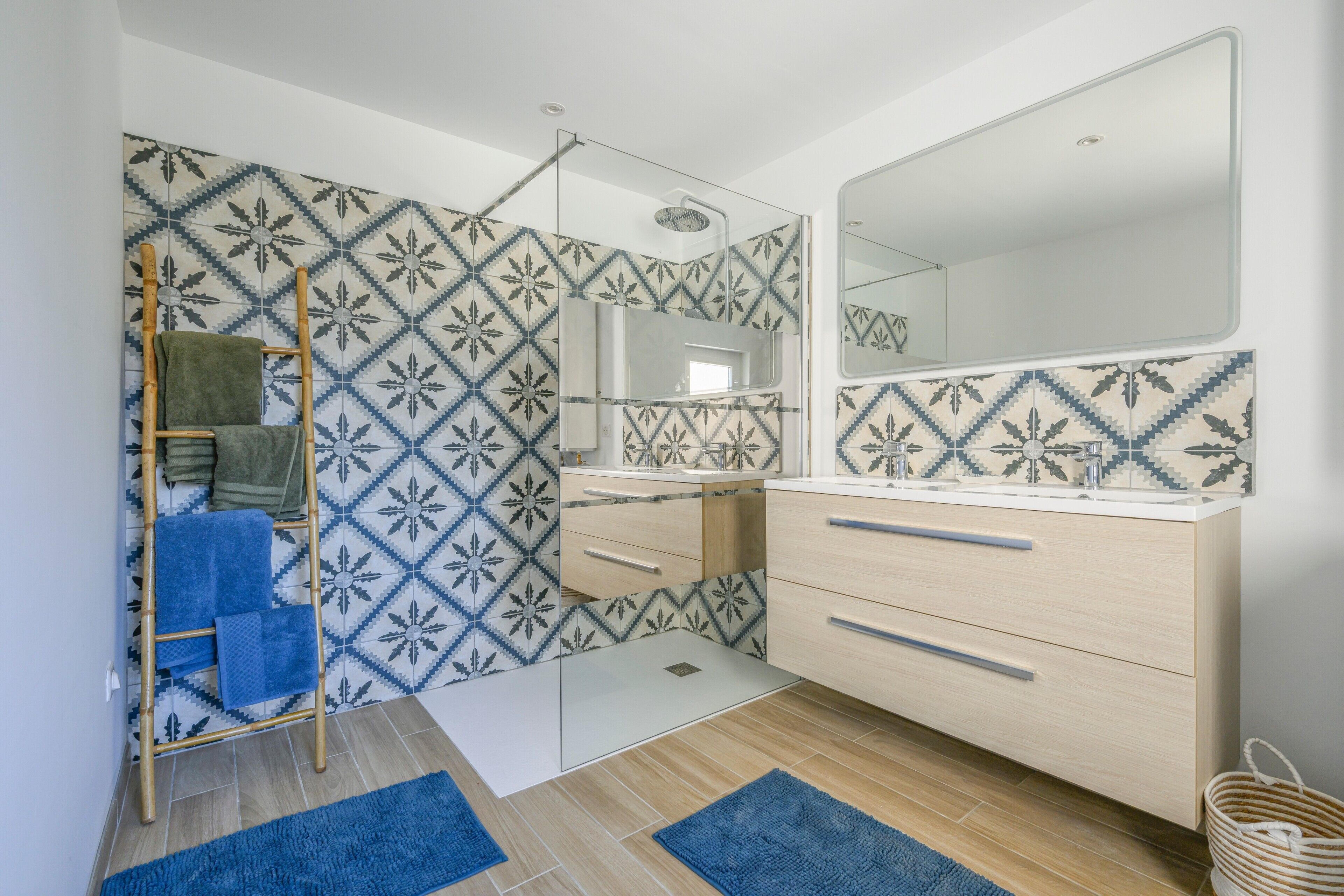 Une salle de bain moderne avec des carreaux à motifs, une échelle en bois, un miroir et un meuble-lavabo en bois.