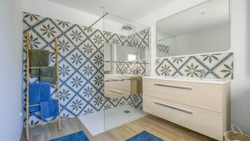Une salle de bain moderne avec des carreaux à motifs, une échelle en bois, un miroir et un meuble-lavabo en bois.