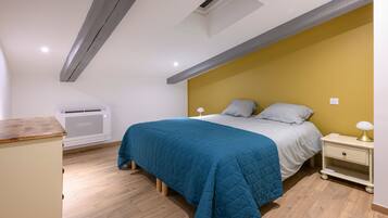 Een slaapkamer met een bed, nachtkastjes, een airconditioning en een houten vloer.