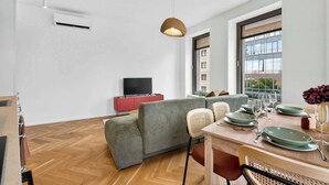 A modern living room with a sofa, dining table, and a television. - Scandi & Modern Apartment in Heart of Bratislava (Bratislava I)