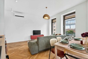 A modern living room with a sofa, dining table, and a television. - Scandi & Modern Apartment in Heart of Bratislava (Bratislava I)