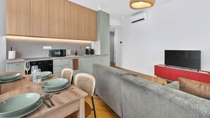 A modern living space with a kitchen, dining area, and a seating area with a television. - Scandi & Modern Apartment in Heart of Bratislava (Bratislava I)