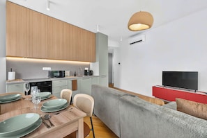 A modern living space with a kitchen, dining area, and a seating area with a television. - Scandi & Modern Apartment in Heart of Bratislava (Bratislava I)