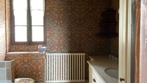 Et badeværelse med trægulv, toilet, radiator og et vindue.