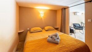 Ein Hotelzimmer mit einem Bett, einer Wandleuchte, einem Sessel und Blick durch eine Schiebetür.