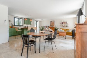 A modern kitchen with green cabinets, a dining area with a wooden table and chairs, and a living room with a sofa and a coffee table. - Maison Marvic en Provence with Private Pool, Mountain Views, and Vineyards (Apt)
