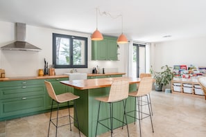 A modern kitchen with green cabinets, a wooden island, and bar stools. - Maison Marvic en Provence with Private Pool, Mountain Views, and Vineyards (Apt)