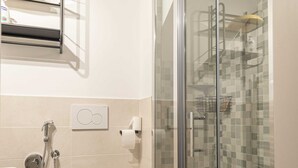Un baño moderno con inodoro, cabina de ducha de vidrio y toallero.