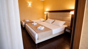 A hotel room with two beds, each with a headboard, a bedside table, and a wall-mounted light. - Hotiday Tropea Parghelia (Parghelia)