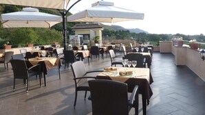 Un patio al aire libre con mesas, sillas, sombrillas y plantas en macetas.