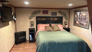 Een slaapkamer met een bed, nachtkastjes, een verwarming en een aan de muur bevestigde televisie.