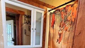 Een badkamer met een houten wastafelmeubel, een grote spiegel en een douchegordijn met een natuurscène.