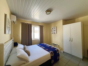 Ein Schlafzimmer mit Bett, Vorhängen, einem Kleiderschrank und einer Deckenleuchte.