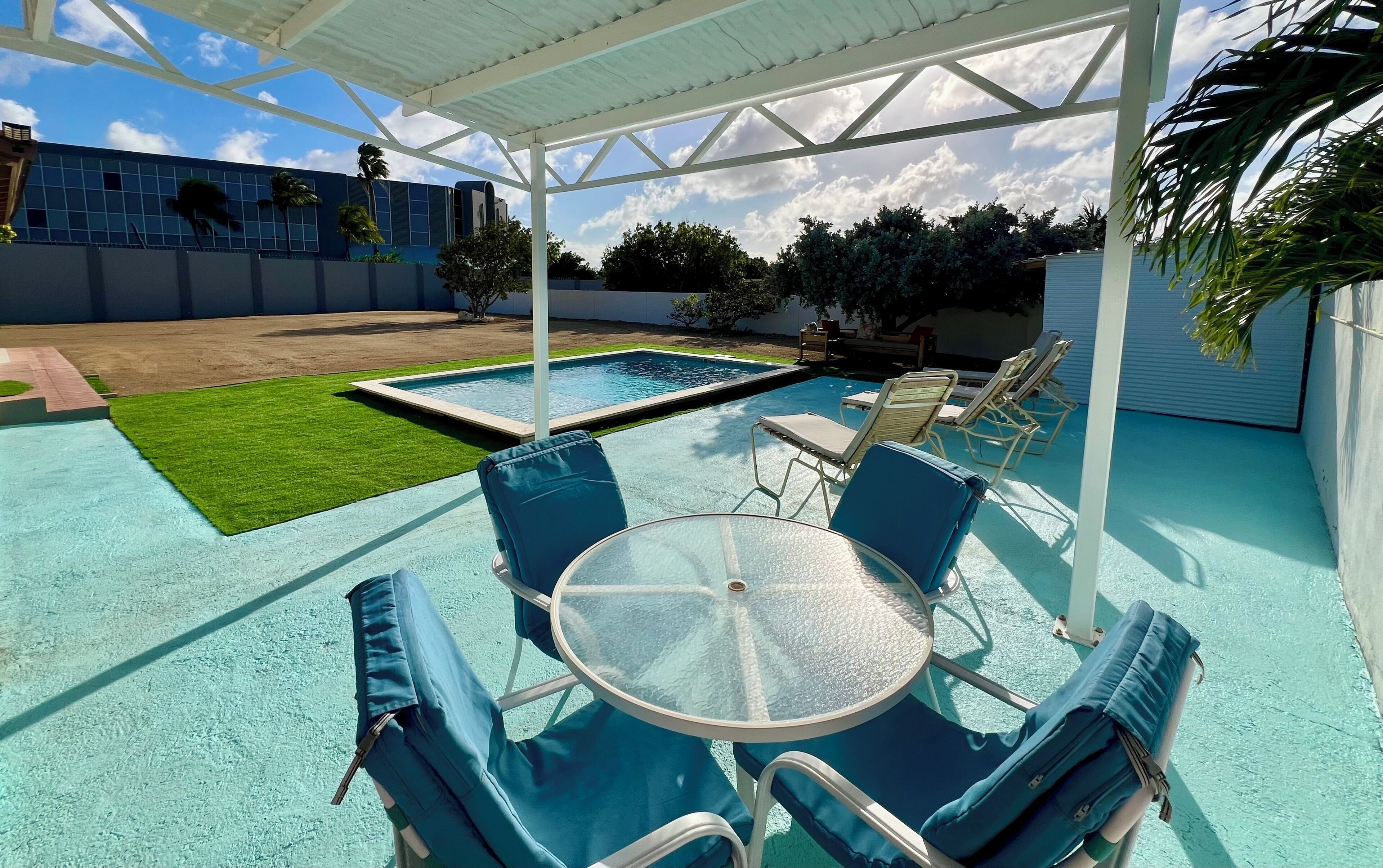 Un espace extérieur abrité comprenant une piscine, des chaises longues et une table.