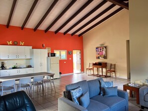 A spacious living area with a sofa, dining table, chairs, and a kitchen with cabinets and appliances. - Villa Emilia  (Oranjestad)