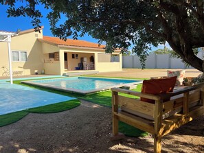 A residential property with a swimming pool, a wooden bench, and a house with a tiled roof. - Villa Emilia  (Oranjestad)