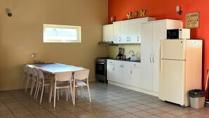 A kitchen with white cabinets, a stove, a microwave, and a refrigerator. - Villa Emilia  (Oranjestad)