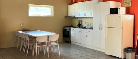 Une cuisine avec des meubles blancs, une cuisinière, un four à micro-ondes et un réfrigérateur.