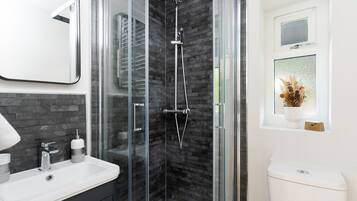 A modern bathroom with a glass-enclosed shower, a white sink, and a toilet.