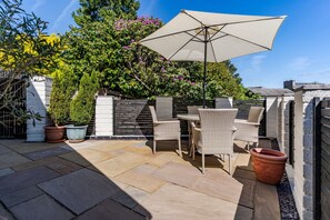 A patio with outdoor furniture, a large umbrella, and potted plants. - South Wales Lodge With Patio (Newport)