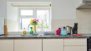 Una cucina con finestra, lavello, bollitore e diversi utensili.