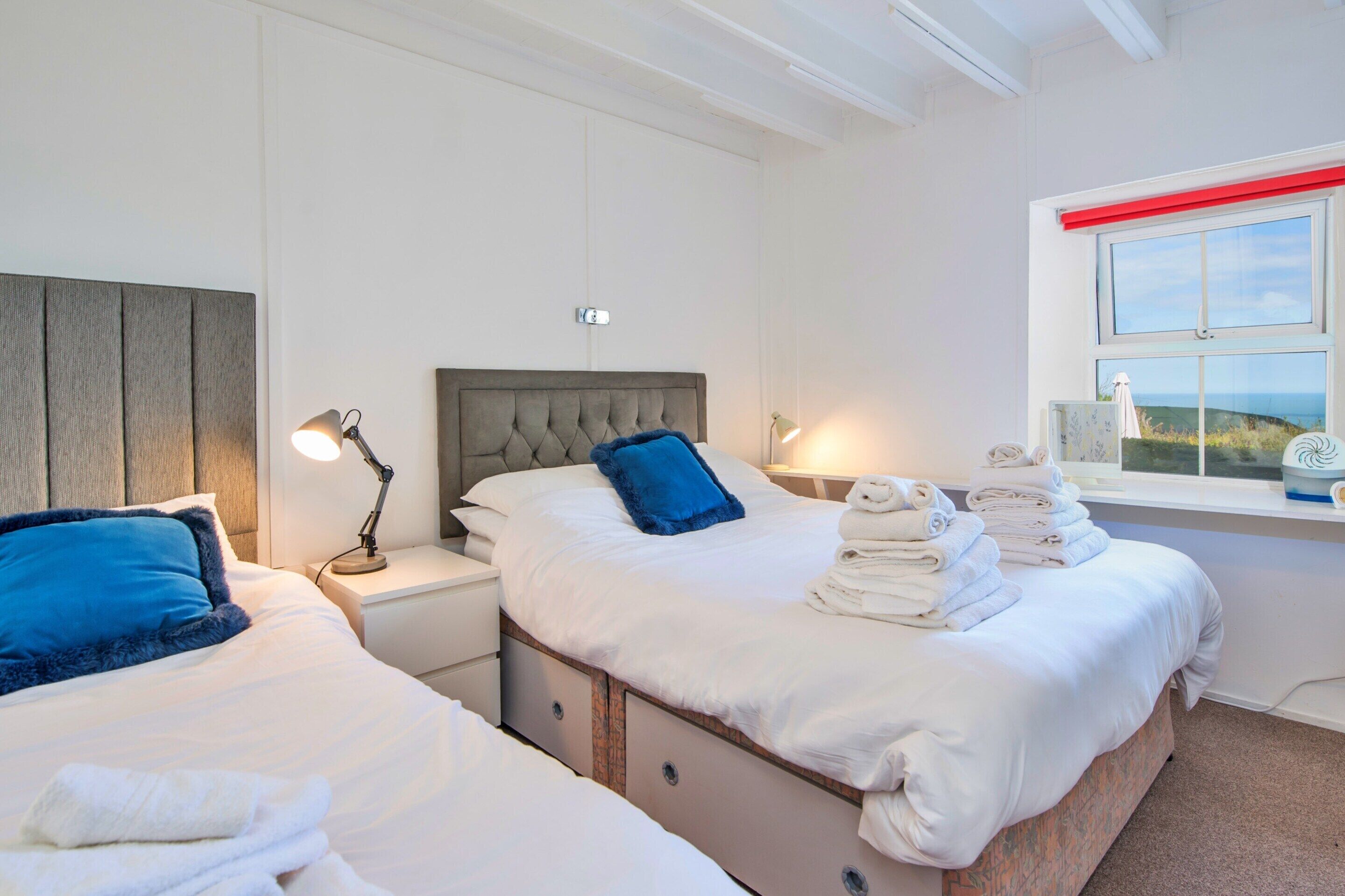 A hotel room with two beds, a window with a view, and a stack of towels.