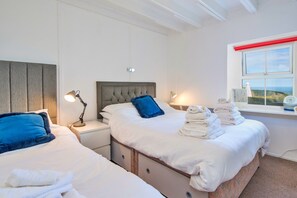 A hotel room with two beds, a window with a view, and a stack of towels. - Charming Snowdonia Slate Cottage (Newport)