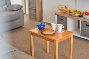 A wooden table with a teapot, two cups, and a plate with croissants in a hotel room. - Charming Snowdonia Slate Cottage (Newport)