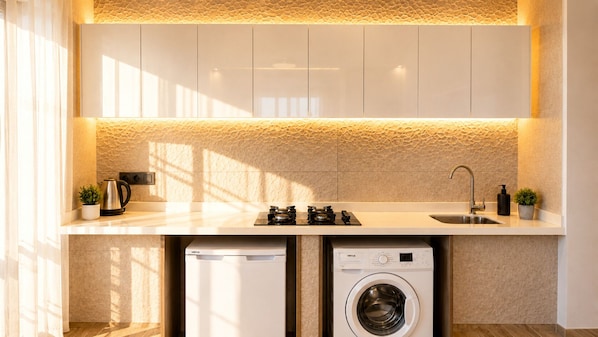 A modern kitchen with a built-in washing machine and dishwasher, a gas stove, and a sink. - Reco Luxury Suit (Ankara)