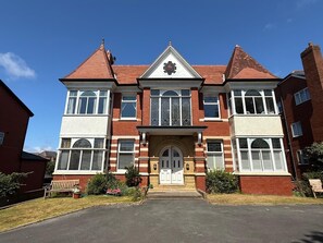 A two-story building with a symmetrical facade, a central entrance with a decorative arch, and a clock above the door.