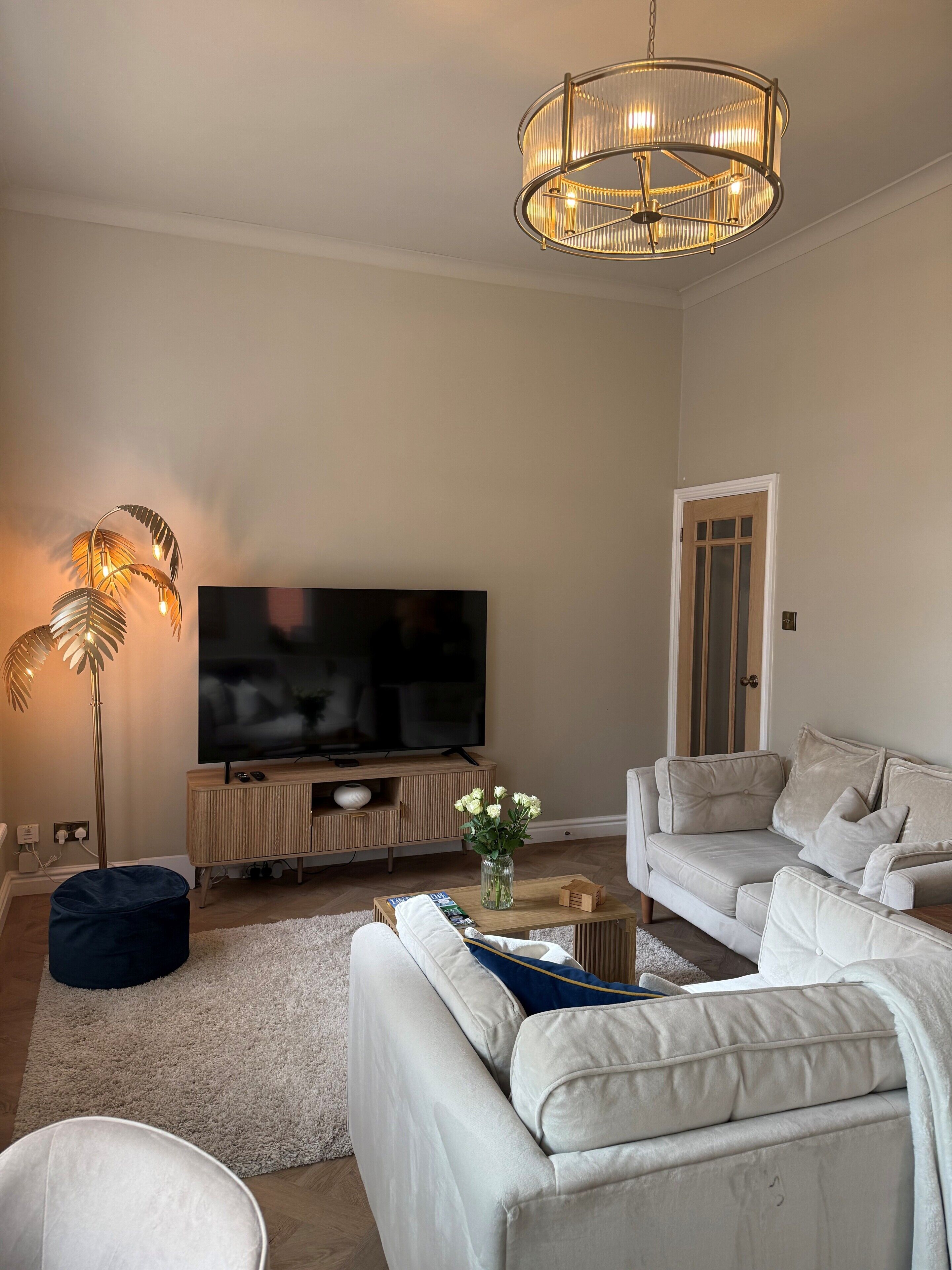 A living room with a flat-screen TV, a sofa, a coffee table, and a floor lamp.