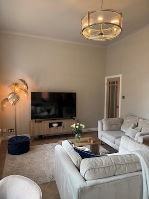 A living room with a flat-screen TV, a sofa, a coffee table, and a floor lamp.