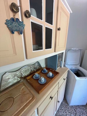 A kitchen with a white refrigerator, a wooden countertop with a tray of blue cups, and a decorative wall piece. - Cozy Mérindol Hideaway In the Heart of the Luberon (Mérindol)