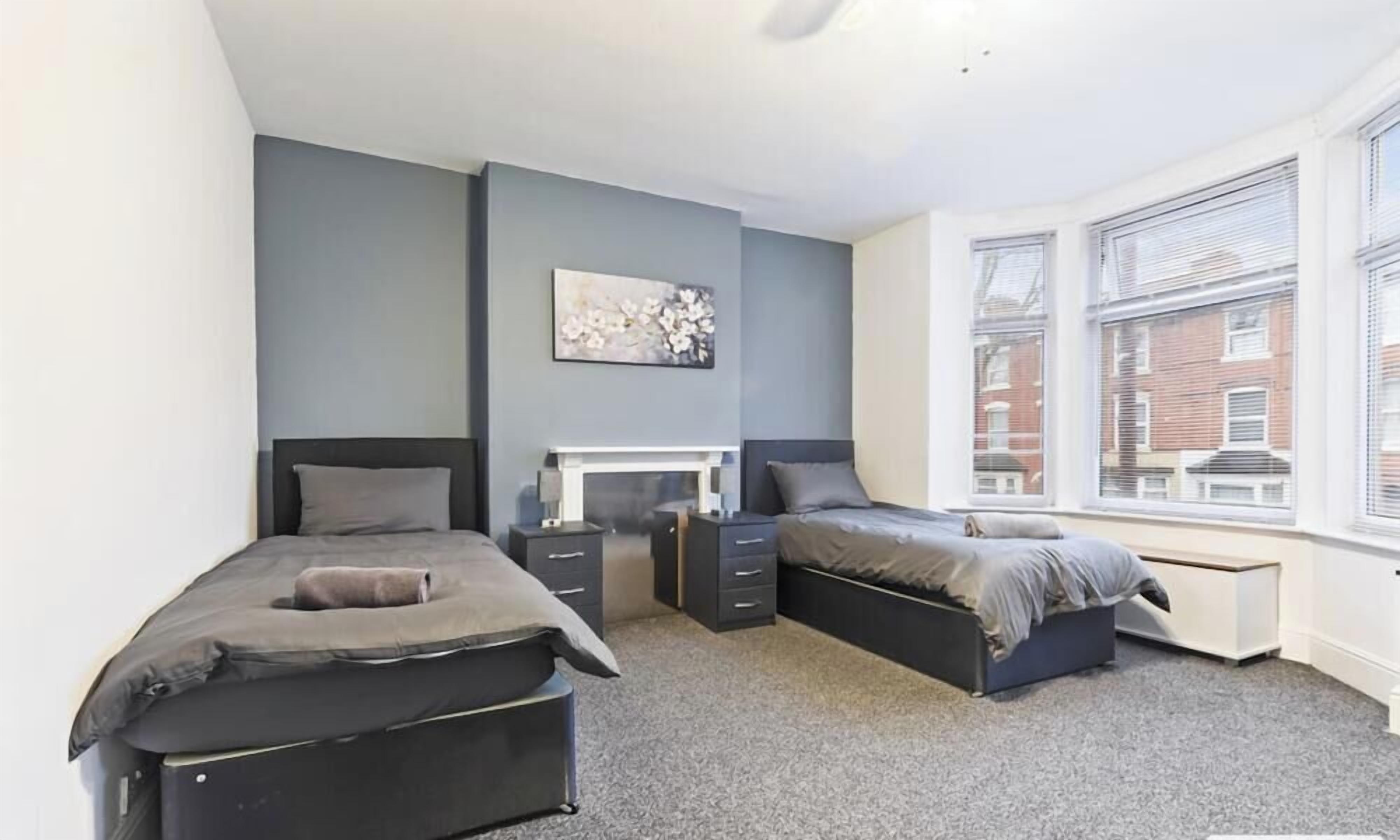 A bedroom with two beds, a desk, and a radiator.