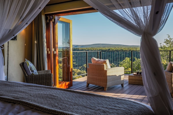 Een balkon met rieten meubilair en een glazen deur naar een prachtig uitzicht.