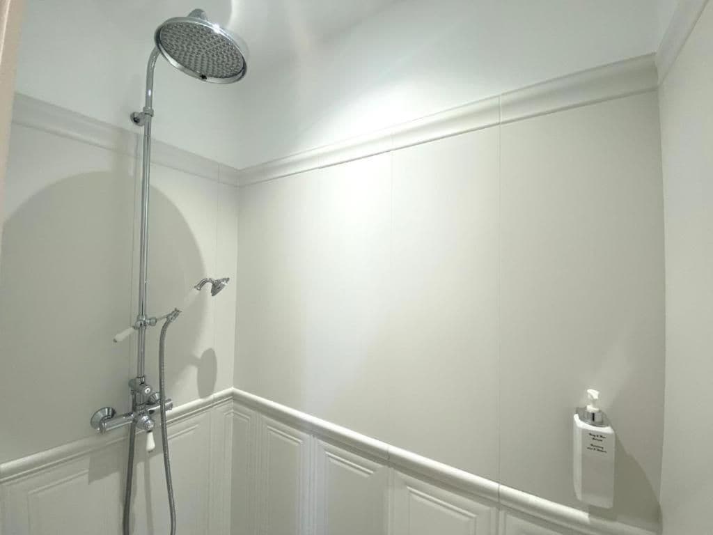A bathroom with a shower, a hand dryer, and a soap dispenser.