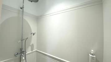 A bathroom with a shower, a hand dryer, and a soap dispenser.